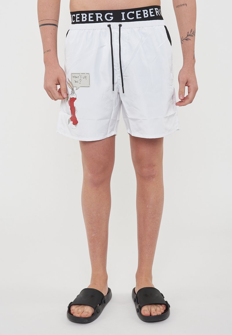 Costume da bagno bianchi con coulisse nera, che presenta un'immagine cartoni animati e il testo "Che succede, Dottore?" sul lato sinistro. Vita con logo nera.