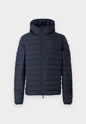 Tumši zils pūkains jaciņa ar kapuci, ar horizontālām šūtām sekcijām, priekšpuses rāvējslēdzēju un elastīgām aprocēm. Minimālistisks dizains ar smalkām akcentiem.