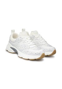 Scarpe sportive bianche con una tomaia in mesh texturizzato che presenta dettagli scintillanti, supporto per il tallone grigio e una suola in gomma beige.