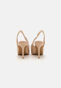 Nude štikle s otvorenom petom, glatka kožna površina i tanke stikle. Minimalistički stil i elegantna silueta.