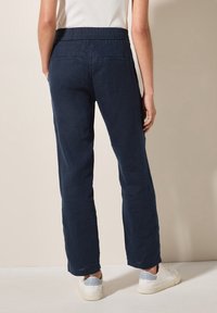 Mörkblå linbyxor med bred ben och elastisk midja, med två bakfickor och en avslappnad passform, i kombination med vita sneakers.