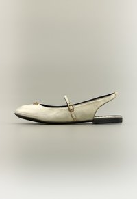 Πλατφόρμα slingback από δέρμα σε κρεμ χρώμα με λεπτό λουράκι και μικρή χρυσή αγκράφα, στρογγυλεμένη μύτη και λεπτή χρυσή διακόσμηση στο μπροστινό μέρος.