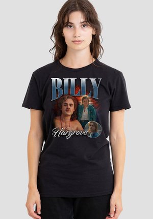 Junge Frau trägt ein schwarzes T-Shirt mit drei Bildern eines Mannes unter dem großen Schriftzug "BILLY" und dem kursiven Schriftzug "Hargrove" auf der Vorderseite.