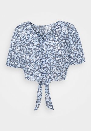 Haut court bleu à fleurs avec un col en V, des manches courtes et un lien à nouer à l'avant. Présente des fleurs blanches et bleu clair sur un fond bleu foncé.