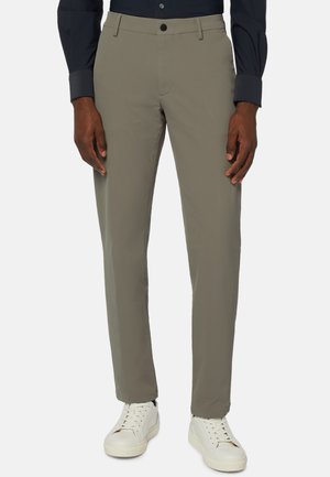 Pantalons gris légers avec une texture lisse, dotés d'une coupe classique et de poches latérales, associés à des baskets blanches.