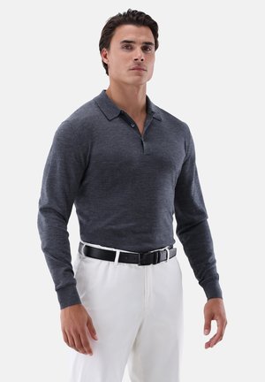 Dunkelgraues Langarm-Poloshirt mit Kragen und zwei Knöpfen, kombiniert mit weißen Hosen und einem schwarzen Gürtel. Glatte Textur, figurbetontes Design.