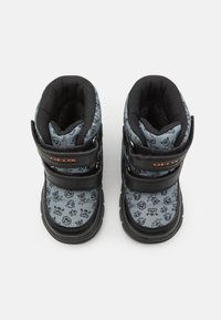 Bottes Geox noires avec un dessus en tissu gris orné de motifs ludiques. Deux bandes Velcro noires sécurisent les bottes. Semelles en caoutchouc pour une meilleure adhérence.