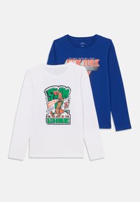 Due magliette a maniche lunghe: una bianca con testo grafico colorato e design di basket; una blu con logo "New York" in rosso e grigio.