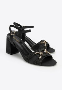 Schwarze Sandalen mit Absatz und offener Zehe. Mit einem strukturierten Riemen mit goldenen Akzenten und einem Blockabsatz. Aus synthetischen Materialien gefertigt.