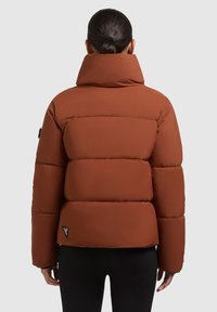 Barna puffjacket magas gallérral, steppelt dizájnnal és elasztikus mandzsettákkal. Az alján logo folt található, és sima tapintású.