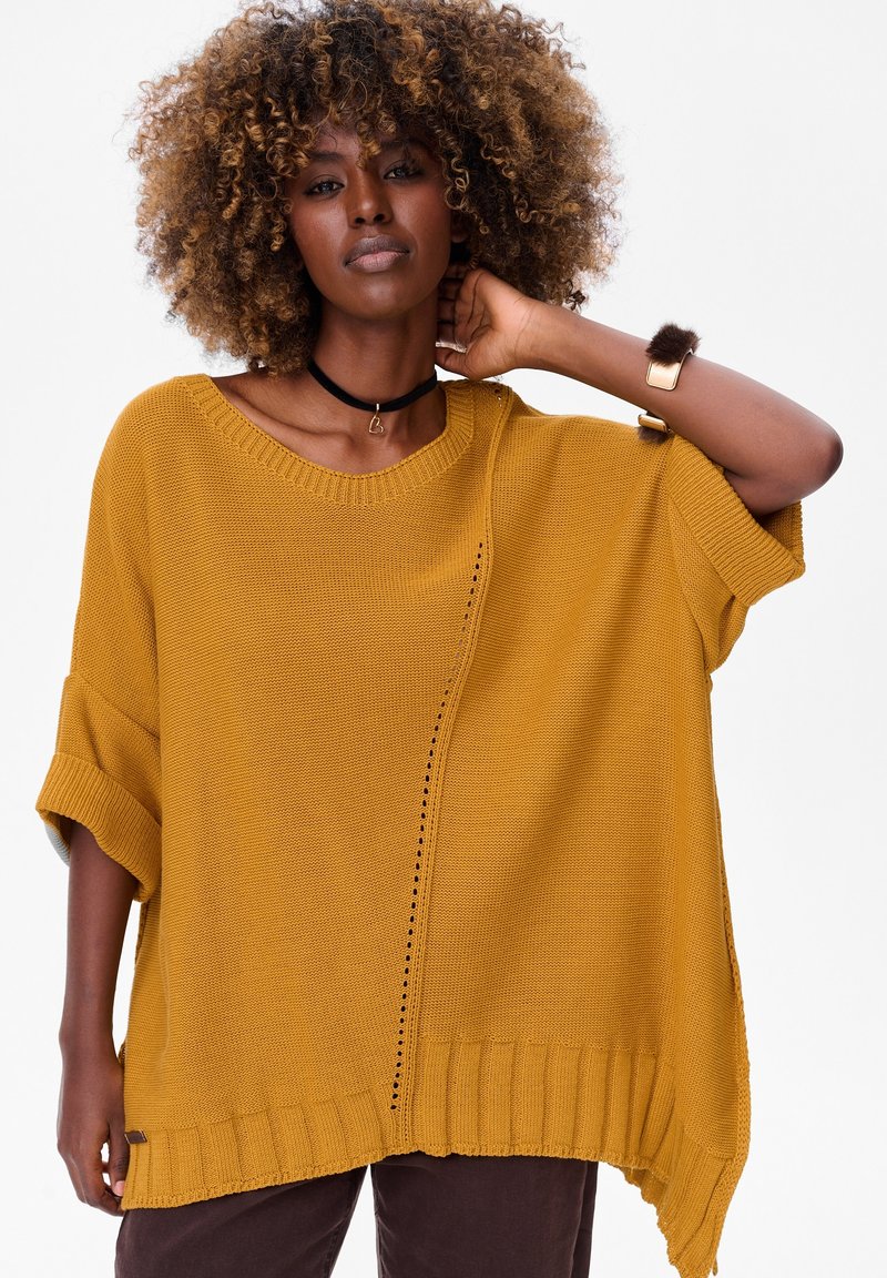 Mosterdgele oversized gebreide trui met korte mouwen, geribbelde zoom en zijsplit. Heeft een decoratief verticale stikselpatroon.