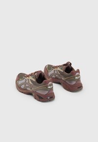 Scarpe sportive in bordeaux e verde oliva, con una parte superiore in rete, suola imbottita e dettagli riflettenti, progettate per comfort e supporto.