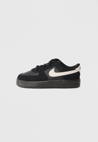 Sneaker in suede nero con punta perforata, suola in gomma nera e logo swoosh bianco a contrasto sul lato. Design atletico a taglio basso.