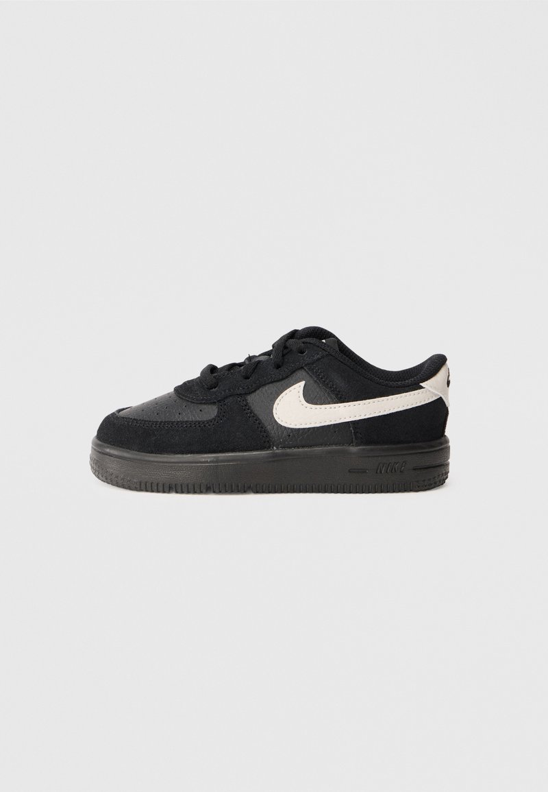 Sneaker in suede nero con punta perforata, suola in gomma nera e logo swoosh bianco a contrasto sul lato. Design atletico a taglio basso.