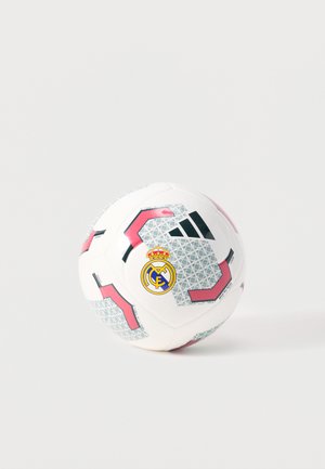 Ballon de football Adidas blanc avec des motifs géométriques roses et gris et l’emblème du club Real Madrid sur un fond clair uni.