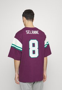 Jersey morado de manga corta con acentos en blanco y azul claro. Muestra el nombre "SELANNE" y el número "8" en la parte posterior en letras grandes y negritas.
