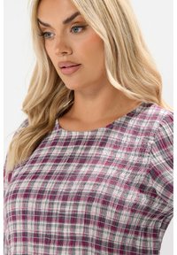 Top a scacchi intrecciati con tonalità di rosa, grigio e bianco. Collo tondo e tessuto testurizzato con dettagli leggermente arricciati sulle spalle.