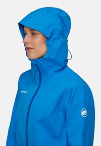 Giacca impermeabile blu con cappuccio, dotata di chiusura con zip e logo sulla manica. Realizzata in tessuto morbido e traspirante.