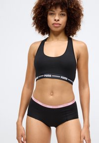 Fekete sportmelltartó széles pántokkal és logóval a szalagon; hozzá illő fekete boyshorts, rózsaszín derékkal.