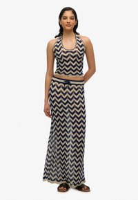 Hæklede halterneck-top og maxiskørt sæt med et navy og creme zigzag mønster. Blød tekstur med snoretræk i taljen på skørtet.