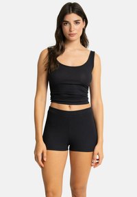 Top court noir à côtes avec larges bretelles et silhouette ajustée, associé à un short noir à côtes assorti avec une taille élastique.