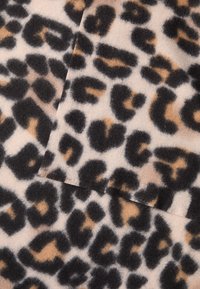 Leopardų rašto audinys su juodais ir rudais dėmėmis ant šviesiai beveik kreminės spalvos fono. Minkšta tekstūra su lengvai pūkuota apdaila.