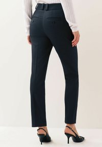 Marintröjor med bakfickor och smal passform. Tyget ser slätt ut med en lätt glans. Bärs med svarta slingbackklackar.