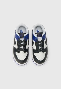 Fekete, fehér és kék Nike tornacipő pár, fűzőkkel, felülnézetből, fehér háttéren.