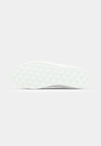 Semelle de sneaker blanche avec un motif texturé et des détails de logo. Fini lisse, forme légèrement courbée, avec un fond plat et un branding subtil.