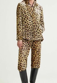 Set di pigiama in raso con stampa leopardata, composto da una giacca con bottoni e pantaloni dalla vestibilità ampia. Presenta una finitura lucida e un colletto classico.