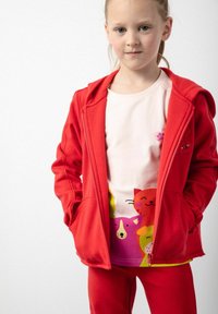 Czerwona polarowa bluza z suwakiem i kieszeniami z przodu, zestawiona z jasnoróżową koszulką z kolorowymi grafikami kreskówkowych zwierząt. Czerwone legginsy dopełniają strój.