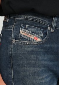 Μπλε τζιν παντελόνια με ξεθωριασμένο φινίρισμα, με ετικέτα στην πίσω τσέπη από τη Diesel Industry, ασημένια μεταλλικά στοιχεία και κλασικό σχέδιο.