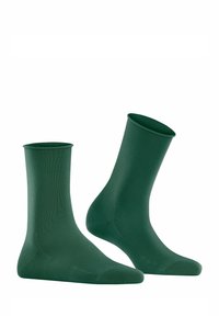 Chaussettes vertes jusqu'aux chevilles, fabriquées à partir d'un tissu doux, présentant une texture unie et un orteil renforcé, avec un design simple et sans couture.