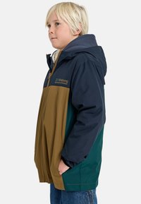 Giacca colorata con pannelli blu navy, marroni e verdi. Ha un cappuccio, una zip frontale e un rivestimento morbido visibile vicino al colletto.