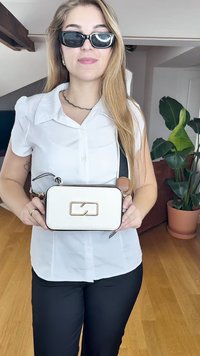 White textured handbag with gold hardware and a rectangular design, featuring a black zipper and a brown accent strap.