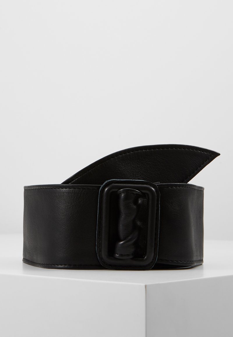Svart lærbelte med en overdimensjonert vridd spenne, med en glatt tekstur og bred bånddesign. Kantene er sydd for holdbarhet.