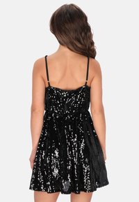 Rochie neagră din mărgele cu un corset ajustat și fustă evazată. Dispune de bretele subțiri și ajustabile și o suprafață texturată din mărgele suprapuse.