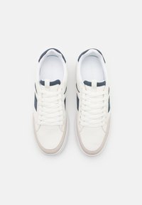 Weiße Ledersneaker mit marineblauen Akzenten, ausgestattet mit einer strukturierten Zehenkappe und runden Schnürsenkeln, designed mit einer gepolsterten Innensohle für zusätzlichen Komfort.