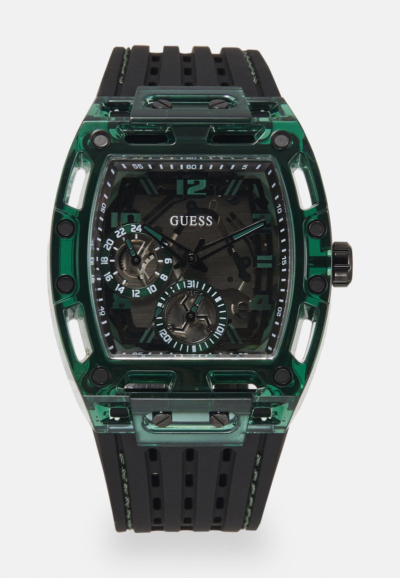 Reloj Guess con caja rectangular de plástico verde, correa de goma texturizada negra y múltiples esferas con números y acentos en negrita.