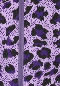 Material cu imprimeu leopard în nuanțe de mov și negru, având o textură netedă, dotat cu un fermoar central și modele vibrante de dimensiuni diferite.
