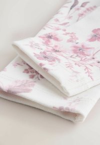 Fehér textil rózsaszín virágmintával, lágy tapintással és bordázott szélekkel. Két összehajtott darab, amelyek zökkenőmentes dizájnt és finom részleteket mutatnak.