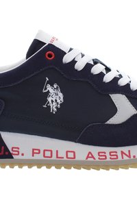 Sneaker in suede blu, con lacci bianchi, dettagli rossi e un logo che rappresenta due giocatori di polo a cavallo. Testo "U.S. POLO ASSN." sulla suola.