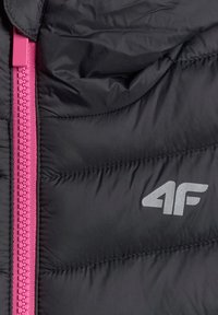 Section de veste matelassée noire avec une fermeture éclair rose vif à gauche et un logo argenté "4F" sur le côté droit du tissu.