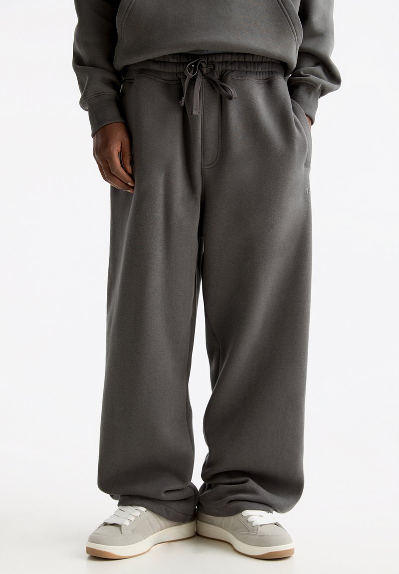 Losse grijze sweatpants gemaakt van zachte stof, met een elastische tailleband, trekkoord en zijzakken.