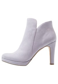 Vaaleanvioletit mokkanahkaiset nilkkurit, joissa on korkea stiletto-korko, pyöreä kärki ja erottuva leikkausdesign sivuilla.