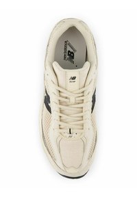 New Balance-sneaker med en beige mesh-överkonstruktion, svart logotypaccent, vävd textur och en dämpad sula för komfort.