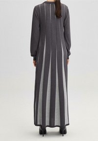 Lang, grijs gebreid jurkje met verticale strepen in lichter grijs. Het heeft lange mouwen, een ronde halslijn en is tot op de vloer. Glad textuur.