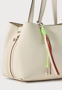 Borsa tote in pelle color crema con superficie texture, caratterizzata da delicati dettagli di cucitura e una charm a nappina multicolore attaccata.