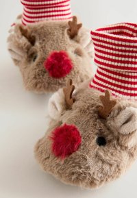 Chaussons en peluche marron en forme de renne avec des nez rouges et des cornes, présentant un poignet rayé rouge et blanc. Texture douce, forme arrondie et design détaillé.