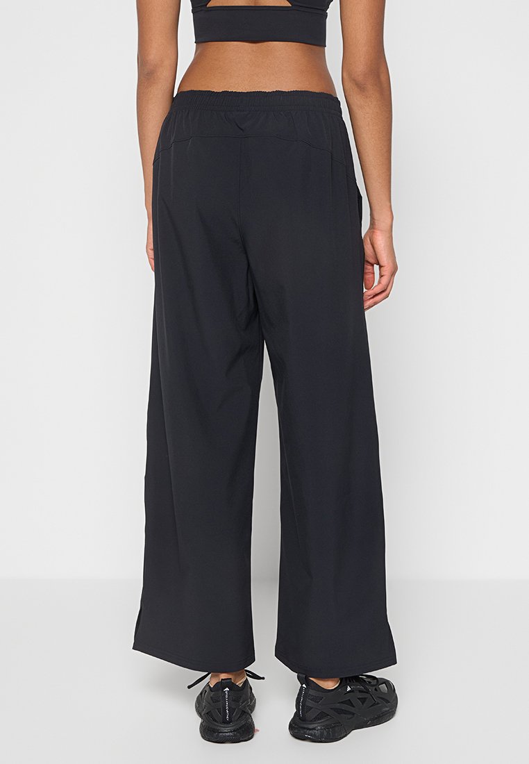 Pantalons larges noirs en matière légère, avec une taille élastique et des poches latérales. Texture douce avec une coupe décontractée.